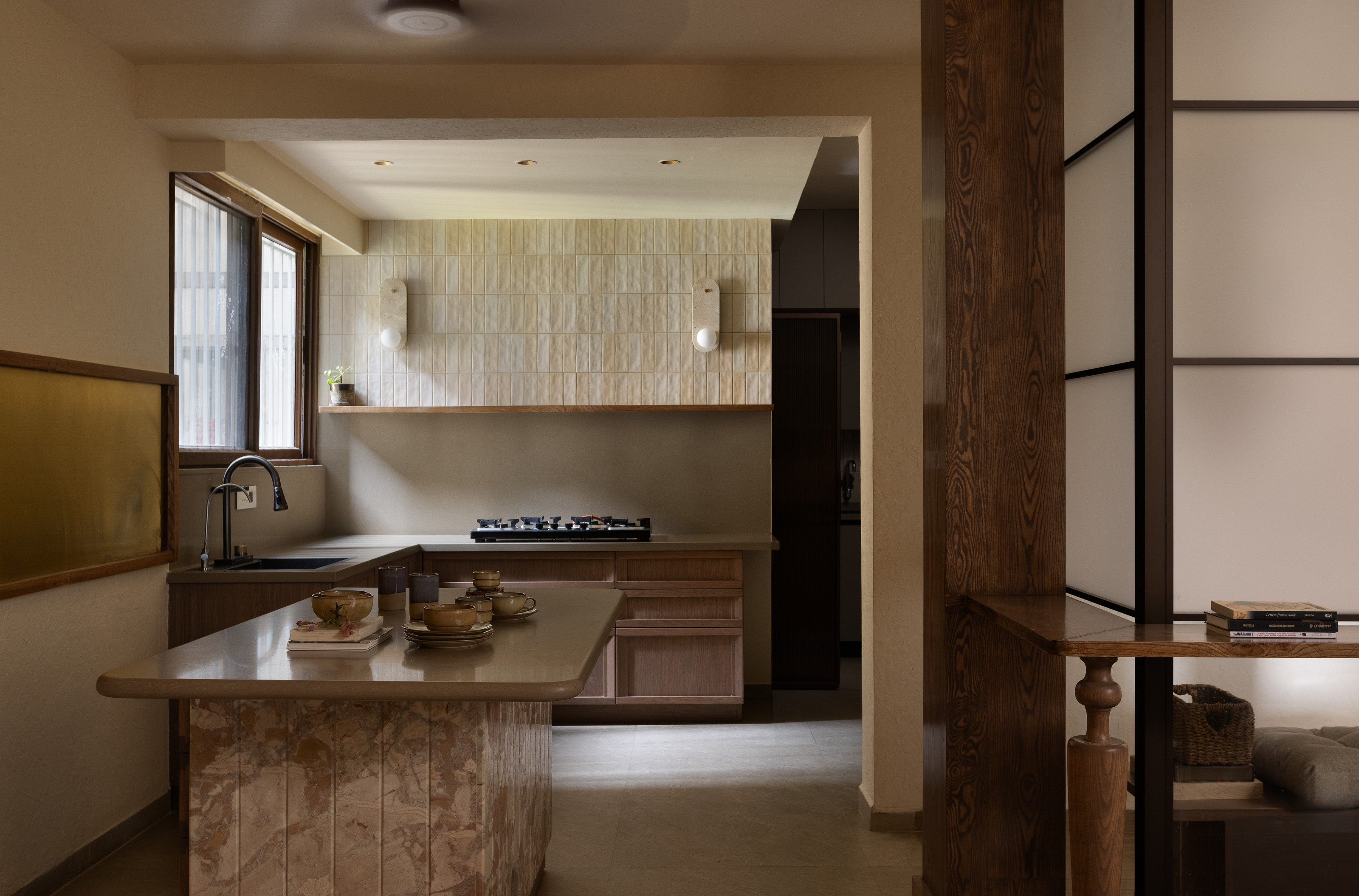 Warm working room with island, bar stools, plants, rhythmic wall panels and shelving