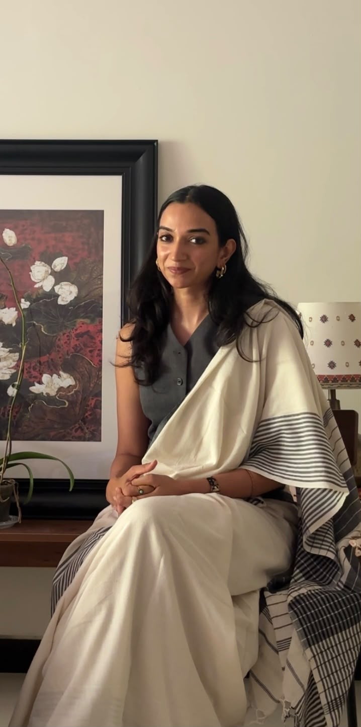 Shvetha, founder and principal architect of Ōraṇi, seated before a framed floral painting